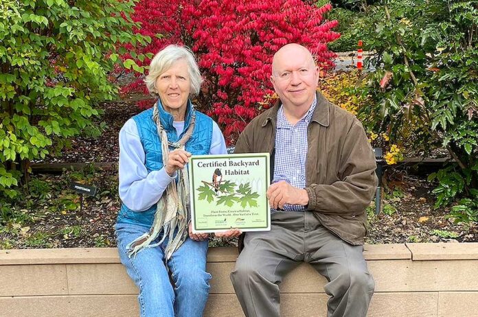 Chris Tunstall (left) and Larry McClure hold a metal plaque designating the historical society’s Backyard Habitat Silver Certification.