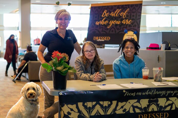 Event organizer Cyndy Hillier (standing) joins volunteer greeters Keira Morthland (left) and Ellie Emery in welcoming guests to Dressed to Dream