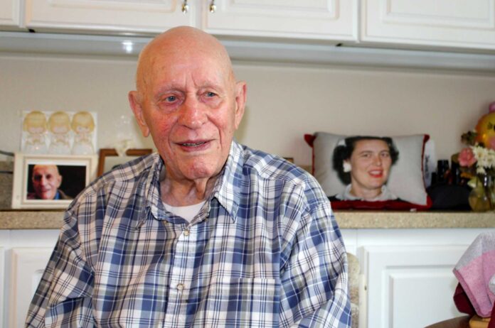 Roland Whitely reminisces about his World War II experiences as a gunner on Merchant Marines ships transporting military supplies around the world. Behind him is a photo on a pillow of his beloved late wife of 71 years, Allene. Barbara Sherman/Tigard Life