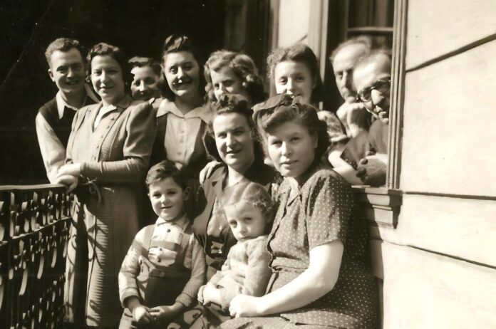Eva’s family, last picture before Eva’s father was taken to forced labor camp. Eva is in front row, sitting on her mother’s lap, and her father is peeking out from the corner of the window. Eva never saw her father again after this day.