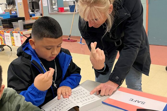 Rotarian Dr. Julie Spaniel practices sign language with a Tualatin Elementary student.