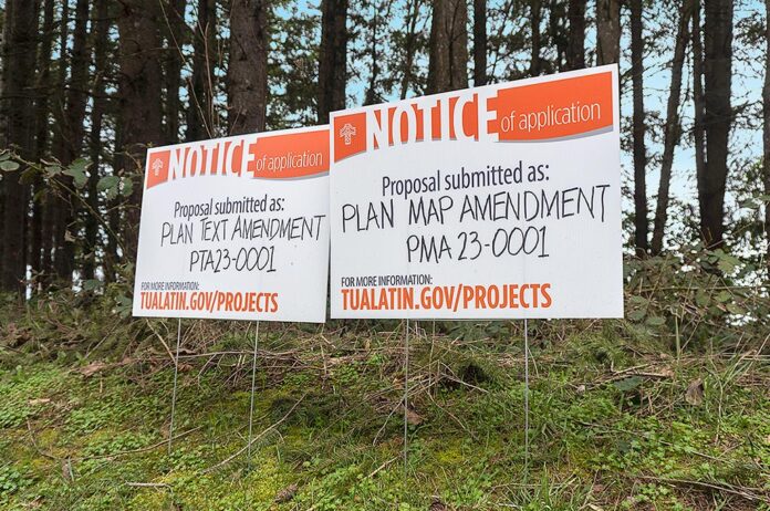 A pair of public notices stand on the property located at the intersection of SW Boones Ferry and SW Norwood Roads.