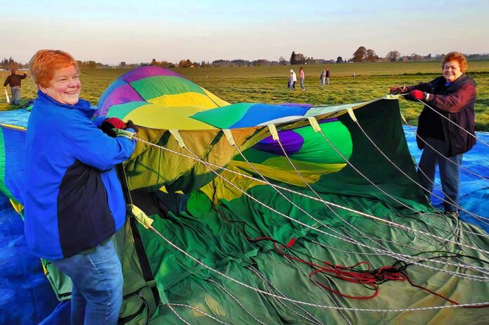 Longtime balloon crew members Marilyn Barnhart (L) and Edie Stoaks hold the opening of a hot air balloon to assist in its inflation. Both women have volunteered on crew since the 1990s.