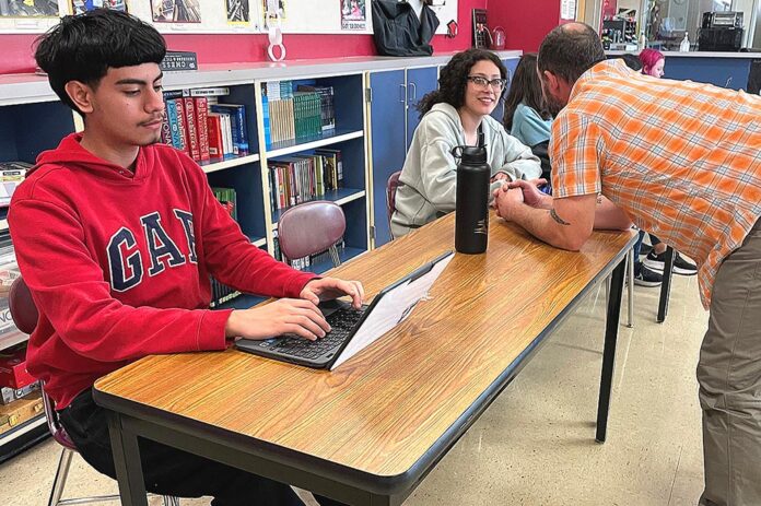 Daniel works on an assignment in Intercambio while advisor Chris Lieuallen speaks to Mia.
