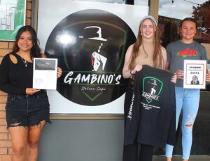 Three Tigard High School students came up with the logos the Johnsons use at the restaurant - (from left) graduate Jasmine Ventura Romero with the logo used on the menu; senior Lily Ingram with the logo used on the clothes; and senior Natalie Church with the logo used in the video poker area.
