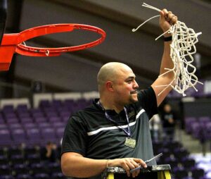 Tualatin Head Coach Bubba Lemon finishes cutting the net after the team's state title win.