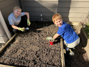 Gardeners Henry and Hailey Fisher planting onions.