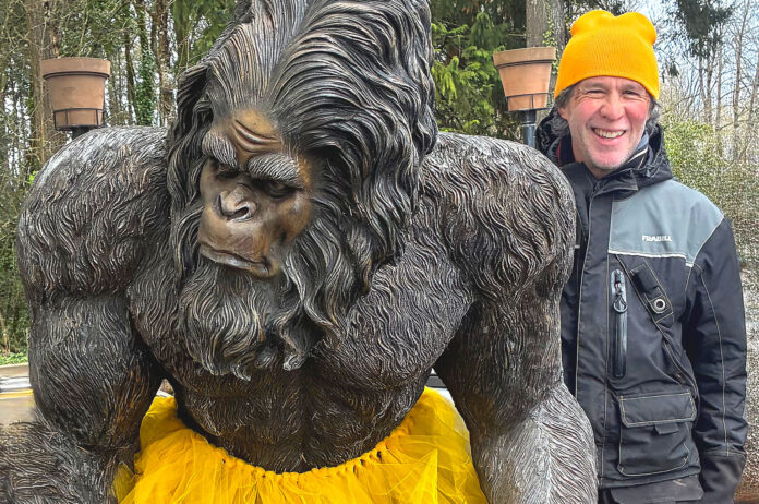 A man with a Bigfoot statue.