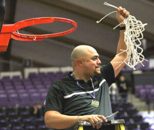 Tualatin Head Coach Bubba Lemon finishes cutting the net after the team's state title win.