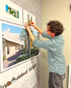 Beck Needham, a third-year student in a five-year architectural program at the University of Oregon, attaches the last elements of his presentation to a wall. Needham was among 16 students who made presentations in a symposium that served as their quarter final exam.