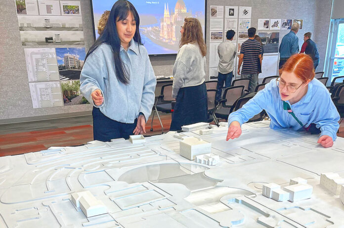 Laura Lopez (left) and Alex Schulte, third-year students in a University of Oregon architectural program, finetune placement of building replicas on a relief map of Tualatin’s downtown. They were participating in a March 10 symposium to exhibit their thoughts on the district’s rejuvenation.