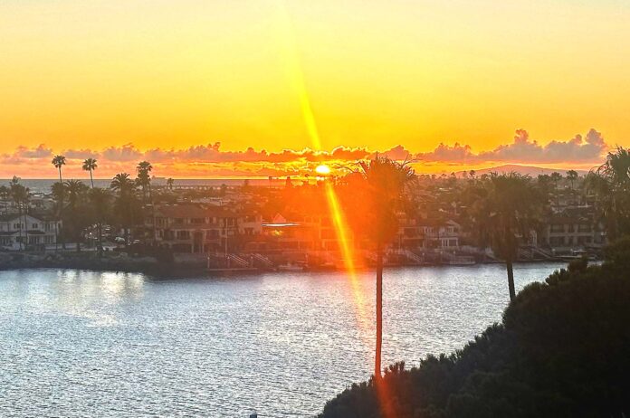 A sun set with a ray of light effect overlooking a bay.