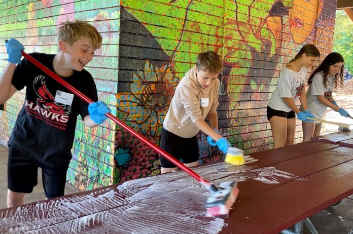 Students washing picnic tables at Community Park shelter.