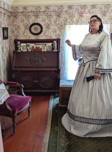 Tualatin Historical Society docent Blake Buchanan-Munro shares details of the North bedroom, one of two featuring a fireplace. Wallpaper was original hung on ragging tacked to rough-sawn boards after Maria Sweek partioned the large upstairs area.