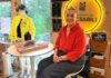 Tualatin Fashion Designer Weaves Stories into Her Work Magsarili sits in front of her neon House of Magsarili sign at her home/office space.