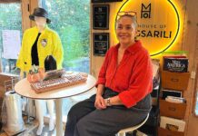Tualatin Fashion Designer Weaves Stories into Her Work Magsarili sits in front of her neon House of Magsarili sign at her home/office space.