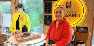 Tualatin Fashion Designer Weaves Stories into Her Work Magsarili sits in front of her neon House of Magsarili sign at her home/office space.