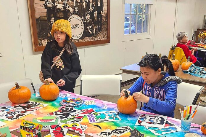 Winona-Grange-Harvest-Festival-Crafts Two people carving pumpkins at a table.